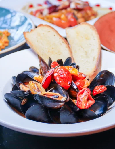 Mussels served with a light spicy garlic white wine sauce, cherry tomatoes, and toasted bread