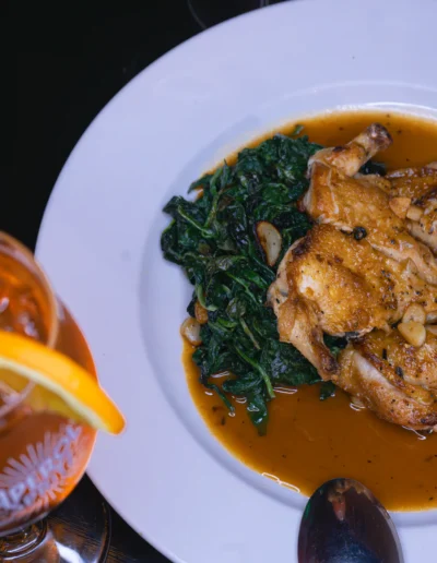 A flattened Cornish hen served with roasted potatoes, green beans, and a pinenut basil pesto sauce